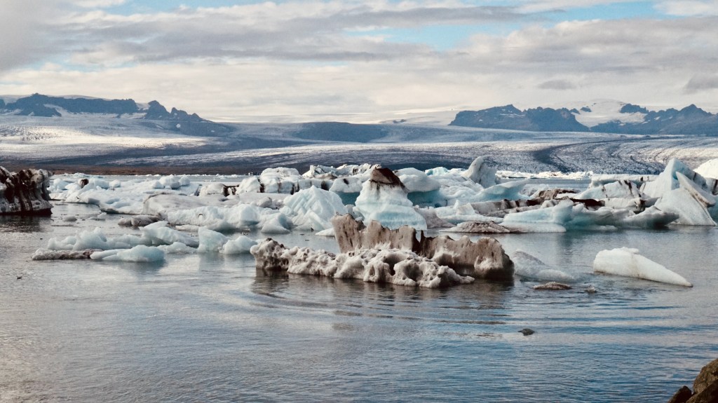 Ice floating in water with mountains in the background